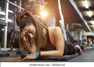 Tired Sporty Woman Lying On Exercise Mat In Gym.