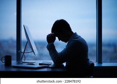 Tired or stressed businessman sitting in front of computer in office