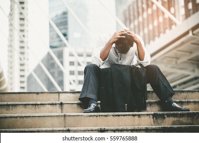 Tired or stressed businessman sitting on the walkway in the city after his work. Image of Stressed businessman concept.