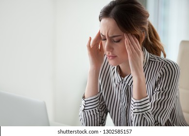 Tired stressed businesswoman feeling strong headache massaging temples exhausted from overwork, fatigued overwhelmed lady executive worker suffering from pain in head or chronic migraine in office