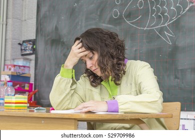 Tired And Stressed Teacher In Classroom