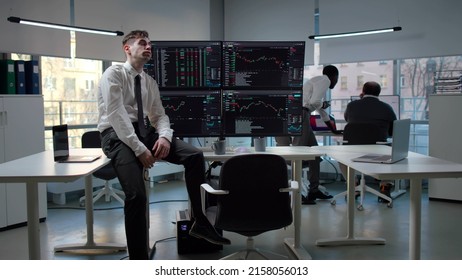 Tired And Stressed Trader Sitting At Desk With Multiple Computer Monitors In Office. Upset Stock Market Broker Lost Money