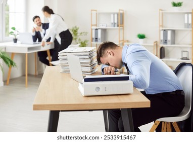 Tired stressed young business working at the desk putting head on table with a pile of documents and folders on his workplace with laptop at office. Overload and overworked concept. - Powered by Shutterstock