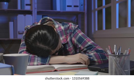 Tired Student Sleeping On Book In Dark Room At Home In Midnight. Exhausted Of Studying Girl Napping While Reading Tutorial Material. College Lady In Glasses Resting On Table Stay Up Late Fell Asleep.