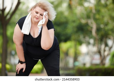 Tired Sweaty Young Plus-size Woman Wiping Forehead After Having Internse Workout Outdoors