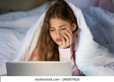 Tired Teenage Girl With Laptop In Bed At Night