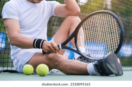 Tired tennis player in sportive clothes sitting on the court, resting after game or training. - Powered by Shutterstock