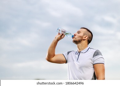 Tired thirsty soccer player on shape taking a break and drinking water. - Powered by Shutterstock
