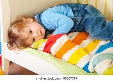 Tired Toddler Laying In His Bed On A Stripped Blanket