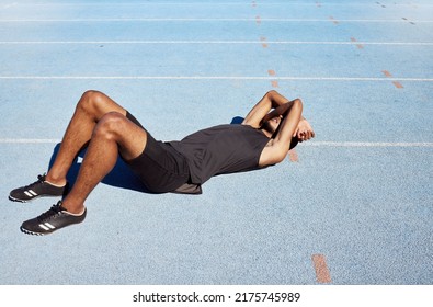 Tired track athlete lying down and feeling exhausted. Active, fit, competitive runner suffering from burnout, heatstroke in training exercise and workout practice. Man covering his face with his arms