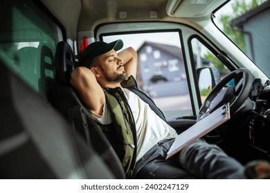 A tired truck driver takes a break from driving and rests in his truck - Powered by Shutterstock