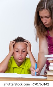 Tired Tween Schoolboy Sitting At The Table With Books While His Angry Mother Standing Next To Him. Sad Female Doing Homework With Her Son. Education Difficulties.