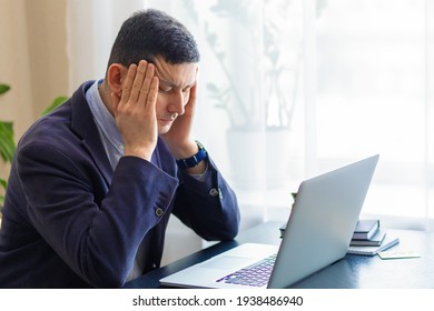 Tired upset businessman, attractive man in suit on workplace for laptop feeling fatigue, stress, headache, migraine due to problems a lot of work, bankruptcy, debts. health of business people.  - Shutterstock ID 1938486940
