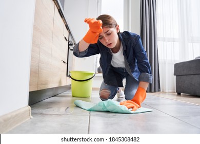 Tired Upset Housewife Wipes Sweat From The Forehead While Collecting Water From The Floor After A Tedious Tap Repair. Stock Photo