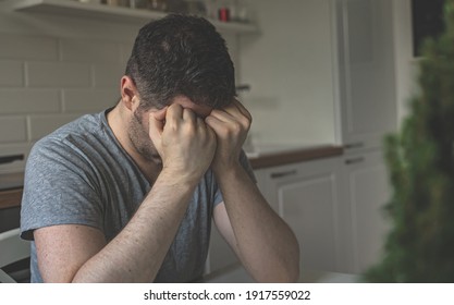 Tired upset man sitting in the kitchen. - Shutterstock ID 1917559022