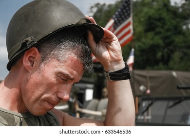 Tired Vietnam War Era Soldier Puts Oh His Helmet, With American Flag In Background (Re-enactment)