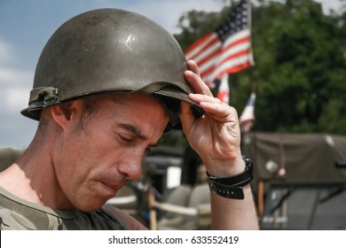 Tired Vietnam War Era Soldier Puts Oh His Helmet, With American Flag In Background