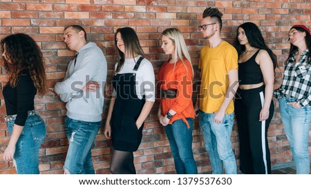 Tired of waiting. Millennials queue. Men women standing in line leaning against brick wall. Moving forward with patience.
