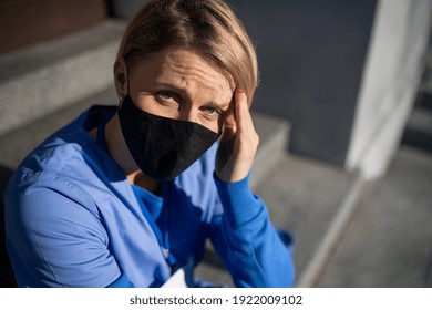 Tired Woman Caregiver, Nurse Or Healthcare Worker Sitting And Looking At Camera Outdoors, Taking A Break.