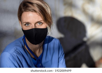 Tired Woman Caregiver, Nurse Or Healthcare Worker Sitting And Looking At Camera Outdoors, Taking A Break.