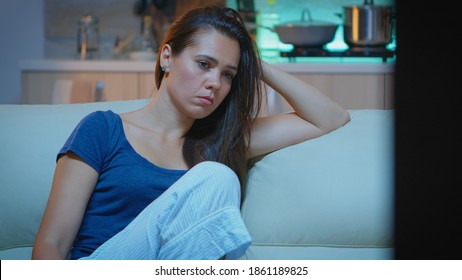 Mujer cansada cerrando los ojos mientras veía películas por la noche. Cansada ama de casa exhausta y solitaria en pijamas durmiendo frente a la televisión sentada en un acogedor sofá en la sala de estar en casa.