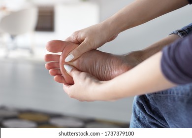 Tired Woman Doing Self Foot Massage For Pain Relief After Fatigue, Long Walking, Working, Standing, Flat Feet Or Injury, Sitting Indoors. Suffering From Hurt Of Arch, Ball, Heel Or Toe Treatment