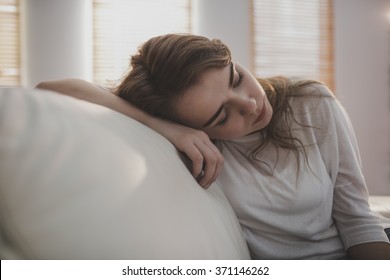 Tired Woman Falling Asleep On The Couch In The Living Room