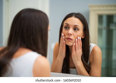 Tired Woman Looking At Her Eye Bags In The Bathroom.