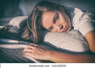 Tired woman lying in bed can't sleep late at night with insomnia. Asian girl with funny face sick or sad depressed sleeping at home.
