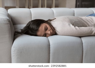 Tired woman lying face down on sofa, close up. Exhausted, depressed, unmotivated female sleep at home. Chronic fatigue, lack of energy, breakdown, frustrated by concerns, housewife and chores concept