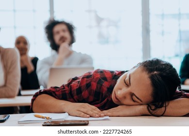 Tired woman napping on the table during a lecture in the classroom - Powered by Shutterstock