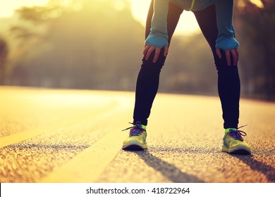 Tired woman runner taking a breathing after running hard on city road