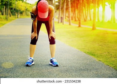 tired woman runner taking a rest after running hard in tropical park trail - Powered by Shutterstock