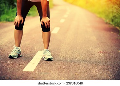 Tired Woman Runner Taking A Rest After Running Hard In Countryside Road. Sweaty Athlete After Marathon Training In Country Road. 