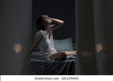 Tired Woman Sitting In Bed At Night With Open Window, She Is Suffering From The Heat And She Is Unable To Sleep