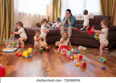 tired woman sitting on a sofa in the room. Child scattered toys. Mess in the house. a lot of children. the little girl plays in the room.