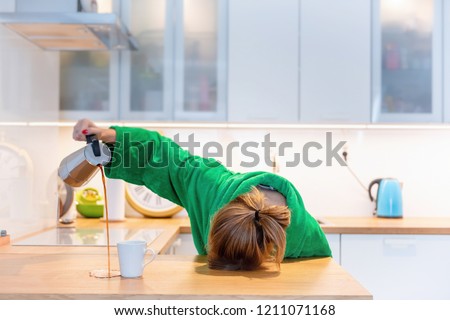 Tired woman sleeping on the table in the kitchen at breakfast. Trying to drink morning coffee