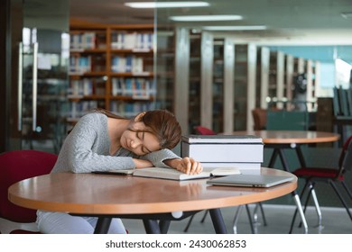 Tired woman student sleeping on desk in library. - Powered by Shutterstock