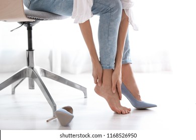 Tired Woman Taking Off Shoes At Office, Closeup View