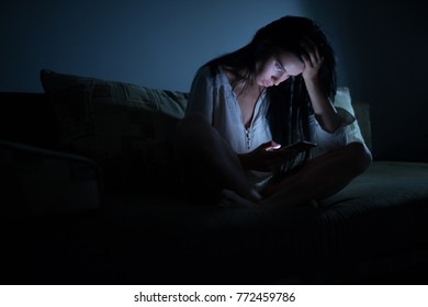 Tired woman using blue smartphone screen at night dark room - Shutterstock ID 772459786