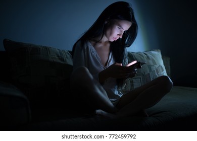 Tired woman using blue smartphone screen at night dark room - Shutterstock ID 772459792