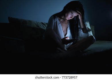Tired woman using blue smartphone screen at night dark room - Shutterstock ID 773728957