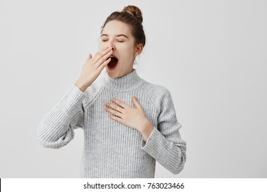 Tired woman yawning covering open mouth with hand need rest. Young female worker being sleepy head can't wake up having insomnia. Chain reaction