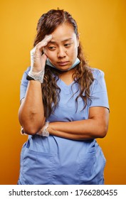 Tired And Worn Down Filipina Nurse Portrait On Orange Background