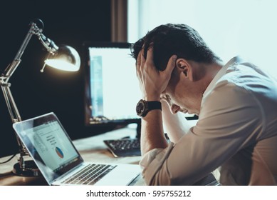 Tired and worried business man at workplace in office holding his head on hands after late night work, concept - Shutterstock ID 595755212