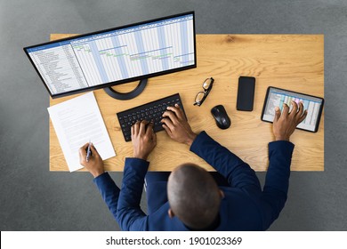 Tired Young African Man Doing Multitasking Work On Laptop In Office - Powered by Shutterstock