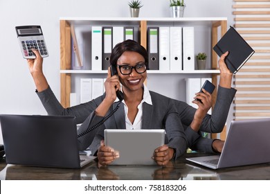 Tired Young African Woman Doing Multitasking Work On Laptop In Office