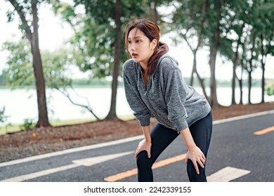 Tired young asian woman resting after running hard in the road at the park after a daily exercise, running jogging for his fitness in the warm summer morning. - Powered by Shutterstock