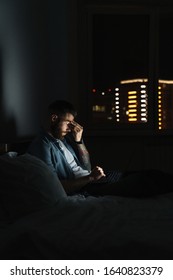 Tired Young Bearded Man Laying On Bed At Home At Night, Working On Laptop Computer