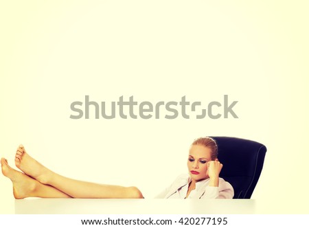 Tired young business woman holding legs on the desk